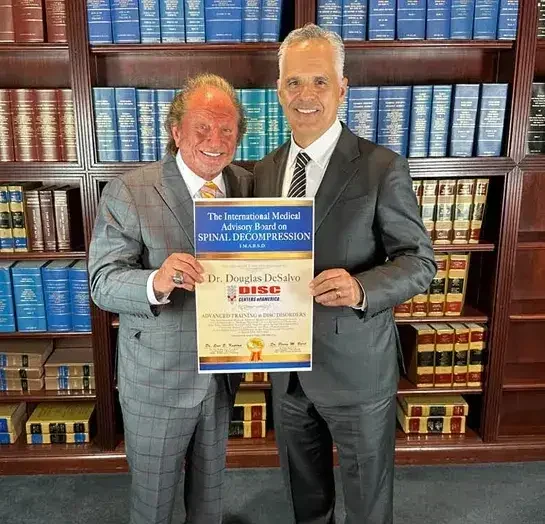 Dr. Douglas DeSalvo holding his International Medical Advisory Board on Spinal Decompression certificate in advanced training in disc disorders